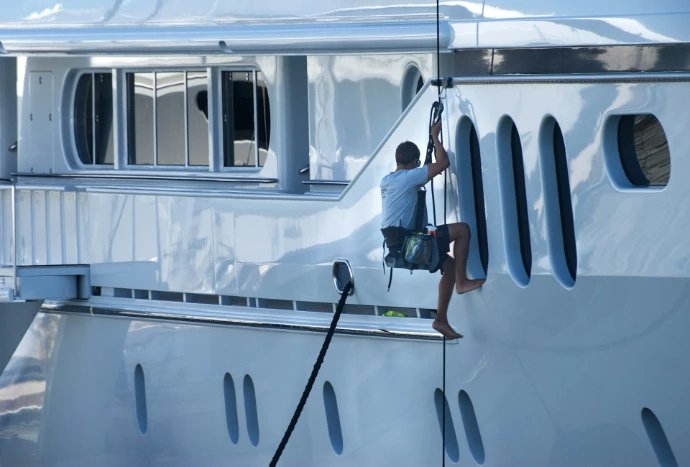 A man is climbing the side of a yacht